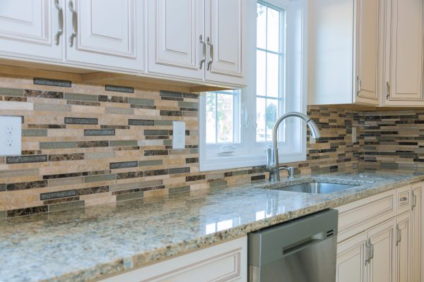 Modern kitchen with light granite countertops and white cabinetry